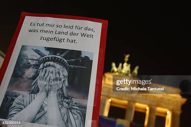 Protesters standing in front of the Brandenburg Gate take part in a gathering to voice their opposition to new U.S. President Donald Trump on the day...