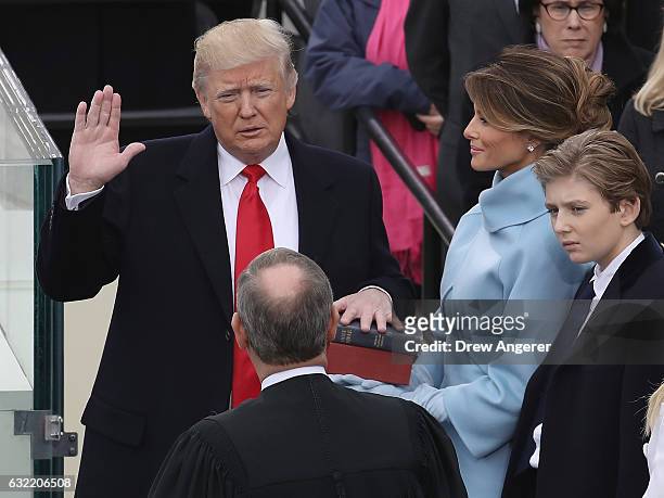 Supreme Court Justice John Roberts administers the oath of office to U.S. President Donald Trump as his wife Melania Trump holds the Bible and son...