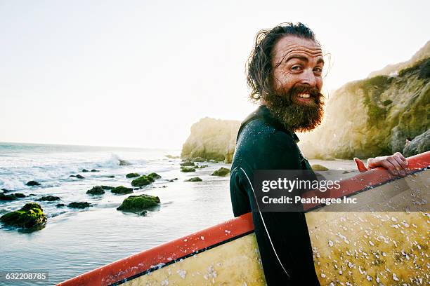 caucasian man holding surfboard at beach - surfer portrait fotografías e imágenes de stock