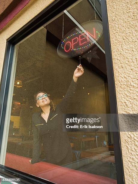 hispanic business owner using open sign - open arms stock-fotos und bilder