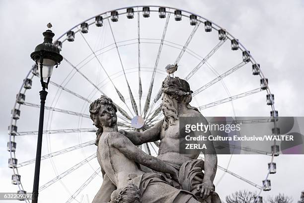 view of statue and grande roue ferris wheel, paris, france - roue stock pictures, royalty-free photos & images