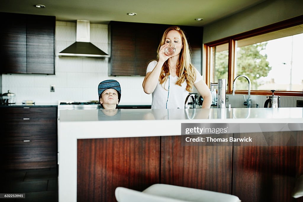 Mother standing in kitchen drinking water