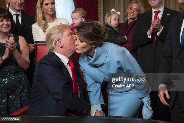 President Donald Trump kisses his wife Melania Trump as he is joined by the Congressional leadership and his family to formally signs his cabinet...