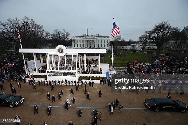 President Donald Trump waves to supporters as he walks the parade route with first lady Melania Trump and son Barron Trump past the main reviewing...