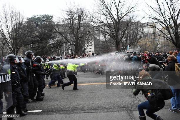 Police pepper spray at anti-Trump protesters during clashes in Washington, DC, on January 20, 2017. . Masked, black-clad protesters carrying...
