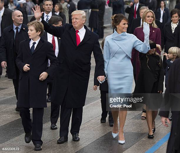President Donald Trump and first lady Melania Trump, along with their son Barron, walk in their inaugural parade on January 20, 2017 in Washington,...