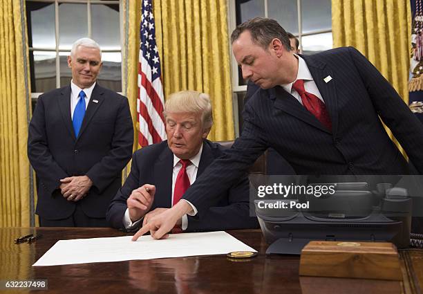 President Donald Trump prepares to sign a confirmation for Defense Secretary James Mattis as his Chief of Staff Reince Priebus points to the order...