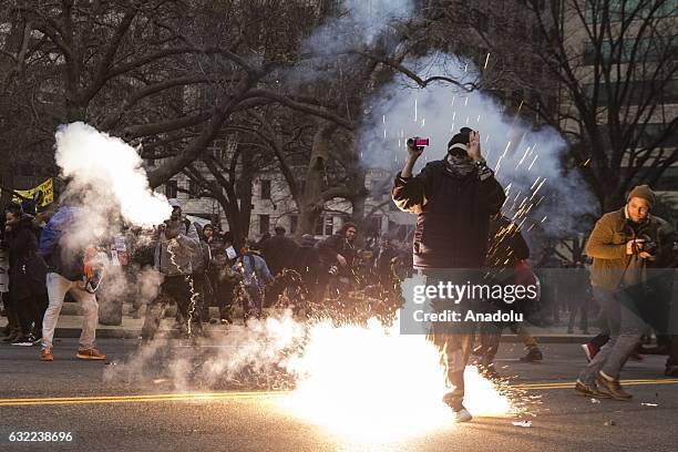 Flash grenade explodes at the feet of an Anti-Trump protestor after protestors set a limousine on fire during clashes with police after President...