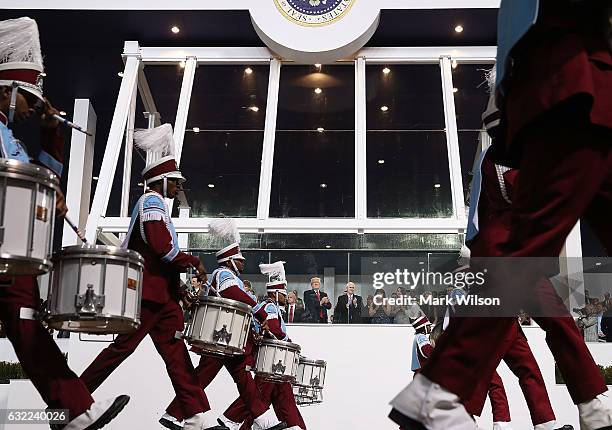 President Donald Trump watches as a marching band passes the inaugural parade reviewing stand in front of the White House on January 20, 2017 in...