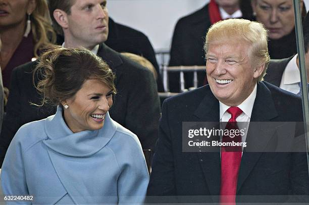 President Donald Trump and First Lady Melania Trump laugh in the presidential review stand outside the White House during the 58th presidential...