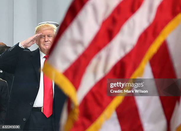 President Donald Trump salutes as an American flag passes the inaugural parade reviewing stand in front of the White House on January 20, 2017 in...