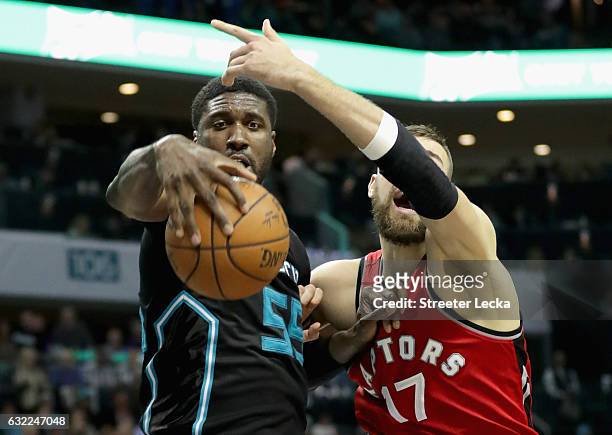 Roy Hibbert of the Charlotte Hornets and Jonas Valanciunas of the Toronto Raptors go after a loose ball during their game at Spectrum Center on...