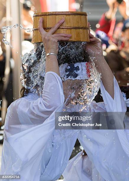 Female participant splashes ice-cold water on herself during the ice water winter purification ceremony on January 21, 2017 in Tokyo, Japan. At...