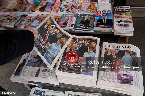 Man picks up a newspaper showing US President Donald Trump on the front pages the day after his inaguration on January 21, 2017 in Madrid, Spain....
