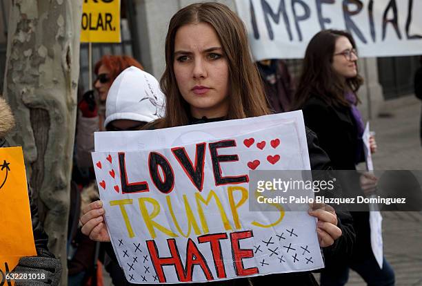 Women holds a placard reading 'Love. Trump. Hate.' during a demonstration in front of the US Embassy on January 21, 2017 in Madrid, Spain. Different...