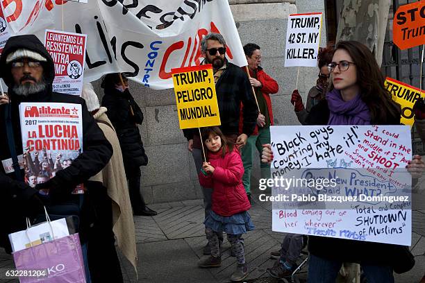 Girl holds a placard reading 'Trump, world danger' during a demonstration in front of the US Embassy on January 21, 2017 in Madrid, Spain. Different...