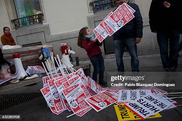 Girl holds placards reading 'Let's lift the resistance against Trump' during a demonstration in front of the US Embassy on January 21, 2017 in...