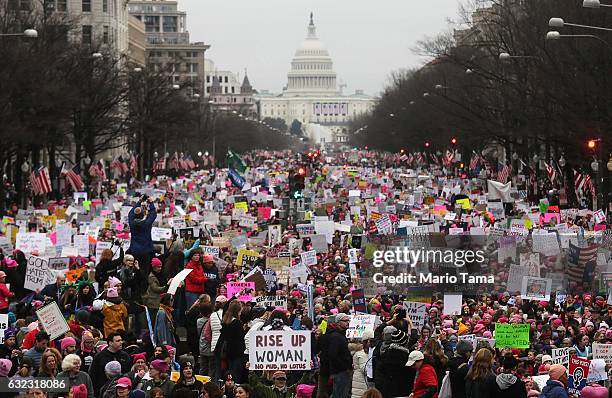 Protesters walk during the WomenÕs March on Washington, with the U.S. Capitol in the background, on January 21, 2017 in Washington, DC. Large crowds...