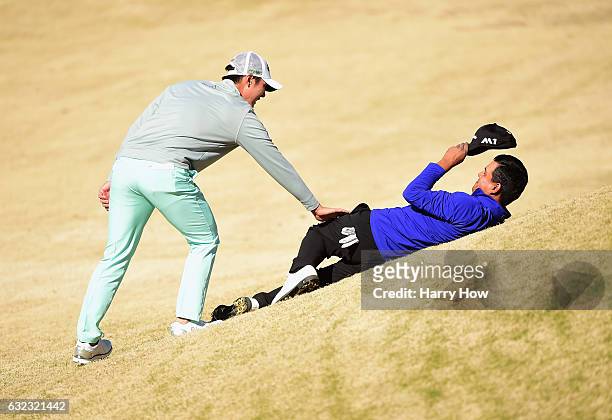 Danny Lee of new Zealand wakes up Fabian Gomez of Argentina who was resting on the side of the tee box on the fifth hole during the third round of...