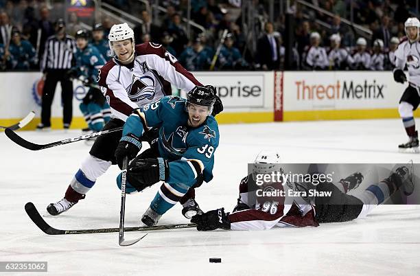 Logan Couture of the San Jose Sharks goes for the puck against Mikko Rantanen and Nathan MacKinnon of the Colorado Avalanche at SAP Center on January...