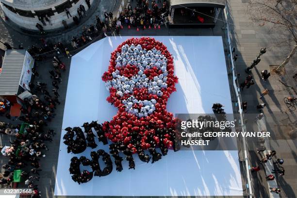People dressed in white and red stand on a white sheet as they form a portrait of the Abbe Pierre, founder of the Emmaus solidarity movement, as...