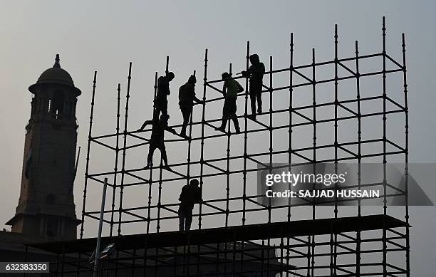 Indian labourers work on scaffolding near the venue of a 'Beating the Retreat' rehearsal ahead of India's Republic Day celebrations in New Delhi on...