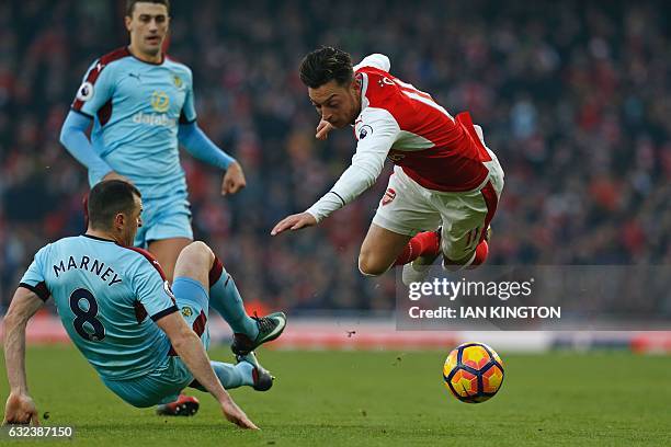 Arsenal's German midfielder Mesut Ozil is tackled by Burnley's English midfielder Dean Marney during the English Premier League football match...