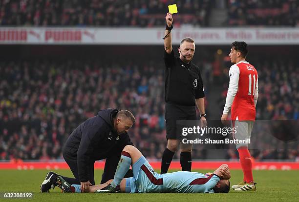 Dean Marney of Burnley is shown a yellow card by referee Jonathan Moss while receiving medical treatment during the Premier League match between...
