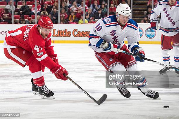 Miller of the New York Rangers skates up ice with the puck followed by Luke Glendening of the Detroit Red Wings during an NHL game at Joe Louis Arena...