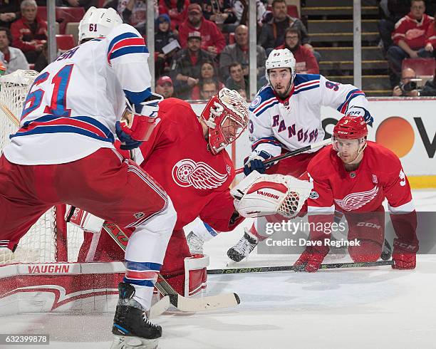 Jared Coreau of the Detroit Red Wings makes a glove save as teammate Nick Jensen defends against Mika Zibanejad of the New York Rangers during an NHL...