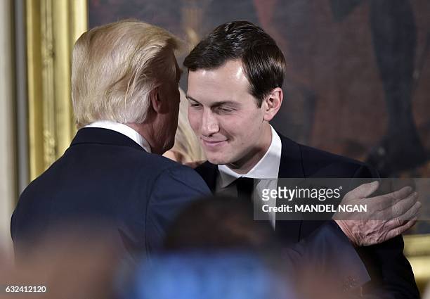 President Donald Trump congratulates his son-in-law and senior advisor Jared Kushner after the swearing-in of senior staff in the East Room of the...