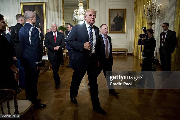 President Donald Trump walks out with U.S. Vice President Mike Pence and Sean Spicer, White House press secretary during a swearing in ceremony of...