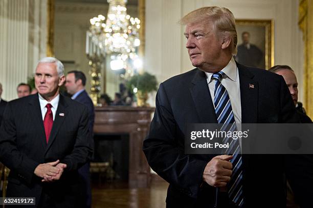 President Donald Trump walks out with U.S. Vice President Mike Pence during a swearing in ceremony of White House senior staff in the East Room of...