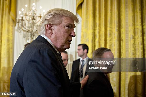 President Donald Trump walks out with Sean Spicer, White House press secretary during a swearing in ceremony of White House senior staff in the East...