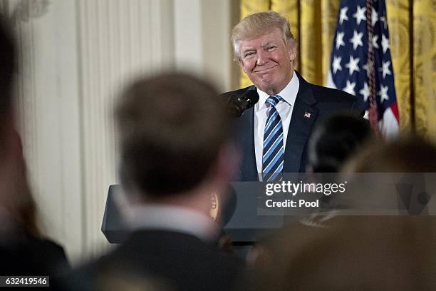 President Donald Trump smiles before speaking during a swearing in ceremony of White House senior staff in the East Room of the White House on...