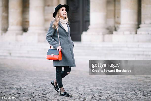 Oceane from the French blog The Blondie World, is wearing a black hat, a gray long coat, a black and red bag, black pants, and black shiny shoes,...