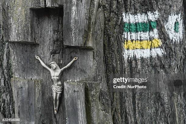 Cross and hiking trails sign on a tree near the church of the Holy Cross 'on Obidowa' in Rdzawka. On Sunday, 22 January 2017, in Rdzawka, Poland.