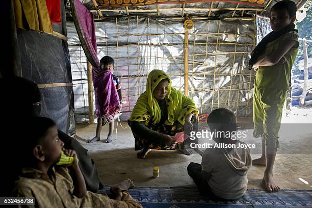 Nojiba sits with friends and family members in her makeshift house that she shares with 14 other refugees on January 20, 2017 in Kutalong Rohingya...