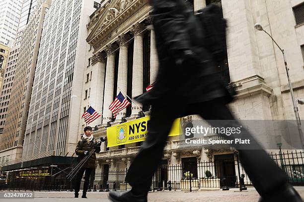 People walk by the New York Stock Exchange on the first day of trading after Donald Trump was sworn in as president on January 23, 2017 in New York...