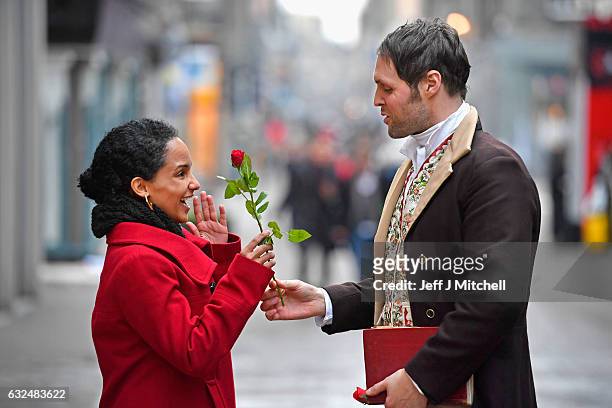 Actor Gareth Morrison dressed as Robert Burns hands a red rose to a tourist to promote the Red, Red Rose Street festival on January 23, 207 in...
