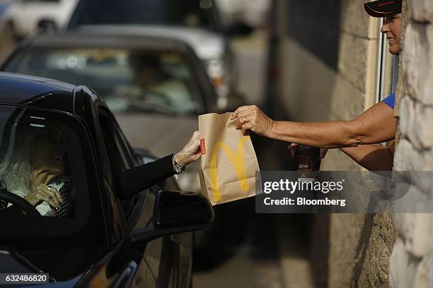 Worker passes a bag of food to a customer at the drive-thru window at a McDonald's fast food restaurant in White House, Tennessee, U.S., on...