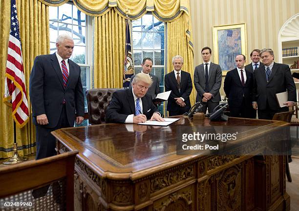 President Donald Trump signs the first of three Executive Orders in the Oval Office of the White House in Washington, DC on Monday, January 23, 2017....