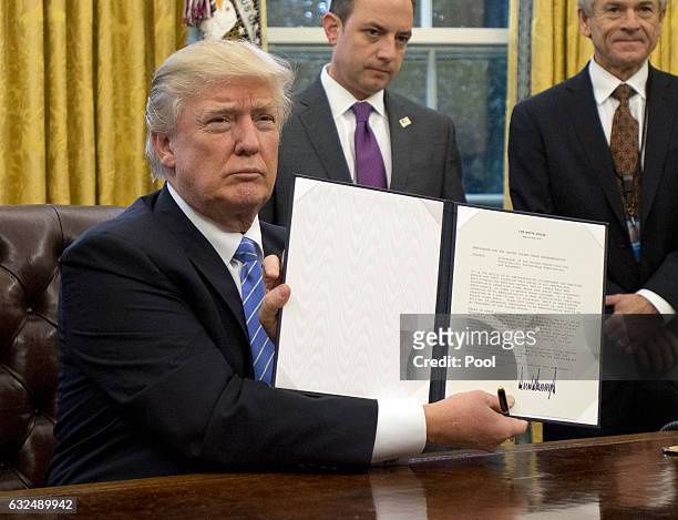 President Donald Trump shows the Executive Order withdrawing the US from the Trans-Pacific Partnership after signing it in the Oval Office of the...