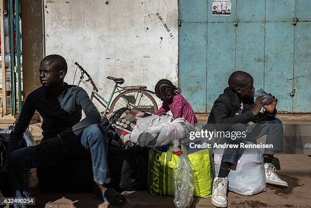 Ulhaji Sesay his sister, Fatemahta and brother, Jibril wait for their mother outside the Banjul Ferry Terminal after returning home on January 23,...