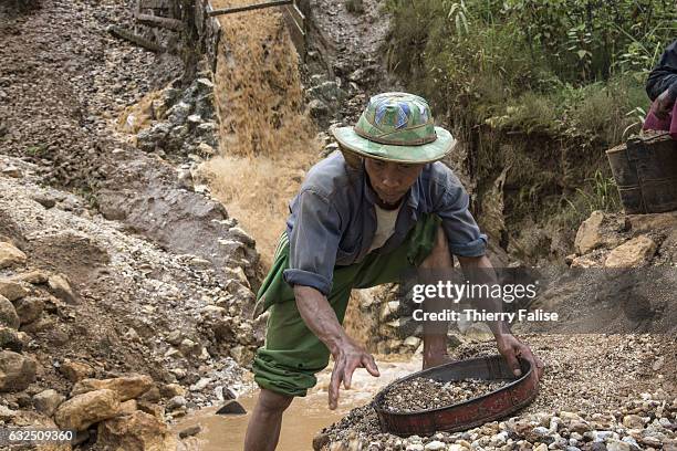 Man uses a sieve to recover stones from the leftovers of a ruby mine located upstream.