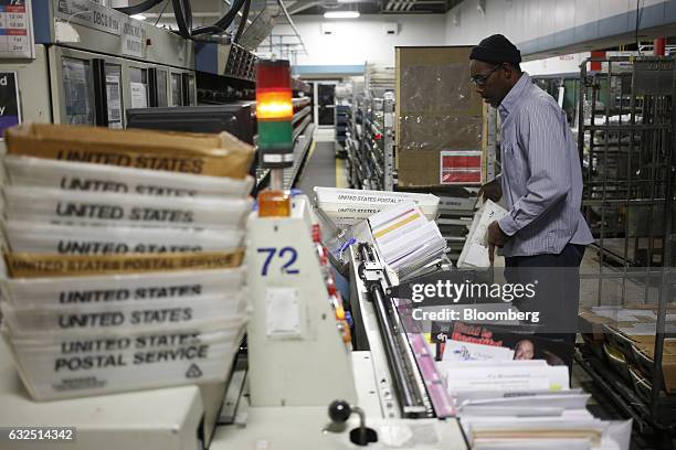 Worker loads mail onto an automated sorting machine at the United States Postal Service sorting center in Louisville, Kentucky, U.S., on Friday, Jan....