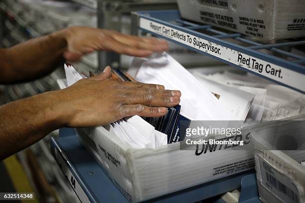 Worker unloads mail from an automated sorting machine at the United States Postal Service sorting center in Louisville, Kentucky, U.S., on Friday,...
