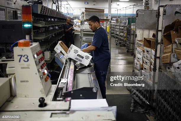 Worker loads mail onto an automated sorting machine at the United States Postal Service sorting center in Louisville, Kentucky, U.S., on Friday, Jan....