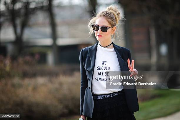 Chiara Ferragni wears sunglasses, a black blazer jacket, a white t-shirt with the inscriptions " We should all be Feminists", a black meshed dress,...