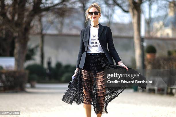 Chiara Ferragni wears sunglasses, a black blazer jacket, a white t-shirt with the inscriptions " We should all be Feminists", a black meshed dress,...